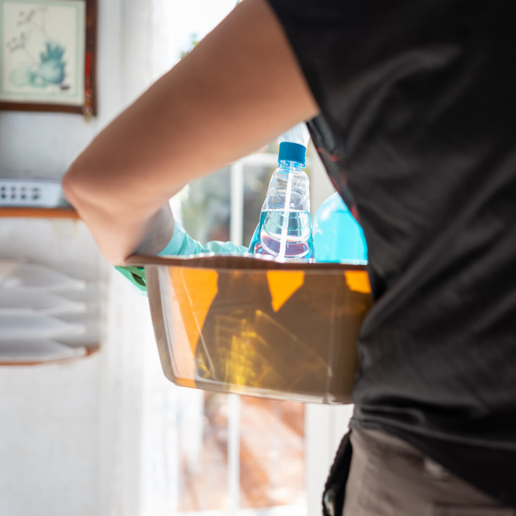Woman on her back holding a bucket full of cleaning supplies to do the cleaning of the home.
